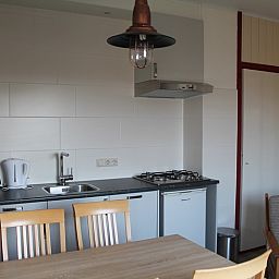 Praktische keuken in vakantiehuis Onder de vuurtoren 115, De Cocksdorp, Texel met moderne apparatuur en eethoek.