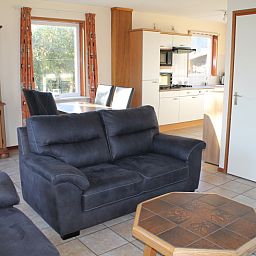 Open kitchen and dining area in Duin-/vuurtorenzicht detached vacation home in De Cocksdorp, Texel with lots of natural light.