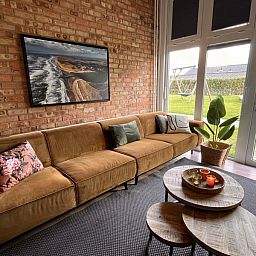 Uitzicht vanuit de woonkamer van Noorderwind vakantiehuis, De Cocksdorp, Texel met grote ramen en tuin.
