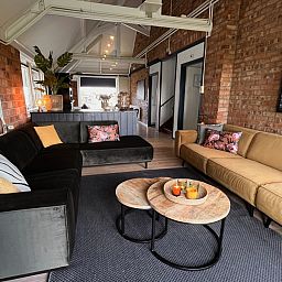 Ruime leefruimte in Noorderwind vakantiehuis, De Cocksdorp, Texel met uitnodigende banken en sfeervolle verlichting.