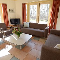 Lichte leefruimte in De Velduil vakantiehuis, Texel met uitzicht op de tuin.