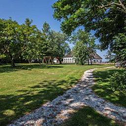 Uitgestrekte tuin rondom Type W vakantiehuis in De Cocksdorp Texel met speeltoestellen.