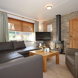 Cozy living room in Villa De Witte Hoek conservatory, vacation home on Texel, with comfortable seating area.