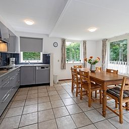 Esszimmer und Kueche des Ferienhauses Slufterduin 098, De Cocksdorp, Texel mit grossen Fenstern.