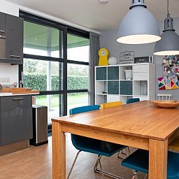 Bright dining area in Holiday home Slufteroord 240, De Cocksdorp with garden views and colorful chairs.