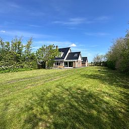 Vast green garden of Family House Dacha in De Cocksdorp Texel, perfect for tranquility and nature experience on the Wadden Islands.