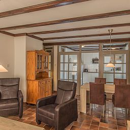 Eet- en zitgedeelte in Type R vakantiewoning, De Cocksdorp, Texel, met houten meubels en warme sfeer.