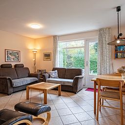 Cozy living room of Holiday home Slufterduin 094 in De Cocksdorp, Texel, with comfortable seating area and views of the green garden.