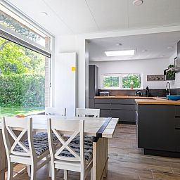 Moderne keuken en eetruimte in Vakantiehuis Slufterhoek 158, De Cocksdorp, Texel, met uitzicht op de groene tuin.
