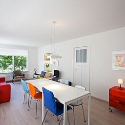 Lichte woonkamer in Bungalow Schelpenoord - Vakantiehuis De Oester, De Cocksdorp, Texel, met kleurrijke stoelen en moderne inrichting.