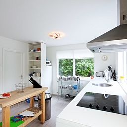Moderne keuken in Bungalow Schelpenoord - Vakantiehuis De Oester, De Cocksdorp, Texel, met kookplaat en uitzicht op de tuin.