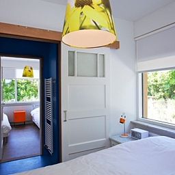 Slaapkamer in Bungalow Schelpenoord - Vakantiehuis De Oester, De Cocksdorp, Texel, met grote ramen en een frisse uitstraling.