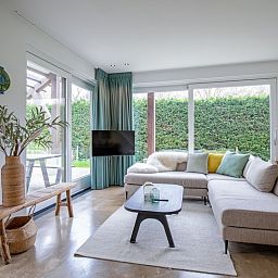 Cozy living room with large window in Holiday home De Razende Bol, De Cocksdorp, Texel, overlooking the garden.