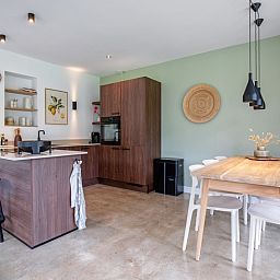 Dining area in Holiday home De Razende Bol, De Cocksdorp, Texel, with wooden table and comfortable chairs.