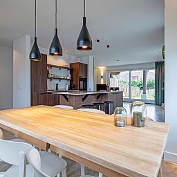 Eetkamer van Vakantiehuis Griend, Texel met houten tafel en sfeervolle verlichting.