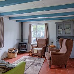 Knusse zithoek in vakantiehuis Muyweg 062, De Cocksdorp, Texel met comfortabele fauteuils en houtkachel.