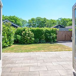 Geniessen Sie die sonnige Terrasse des Bungalows Slufterhoek 108 in De Cocksdorp, Texel, umgeben von der ueppigen Natur der Watteninseln.