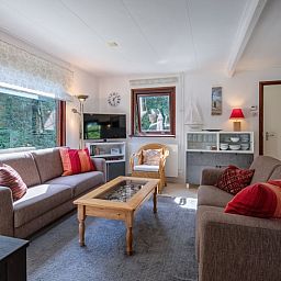 Gemuetliches Wohnzimmer des Ferienhauses Slufterduin 092 in De Cocksdorp, Texel mit bequemen Sofas und viel Tageslicht.