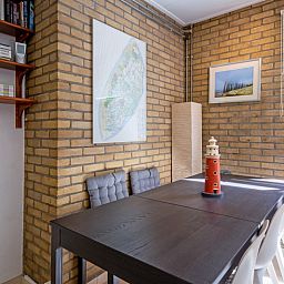 Essecke im Ferienhaus Slufterduin 092, De Cocksdorp, Texel mit moderner Einrichtung und Blick auf die gruene Umgebung.