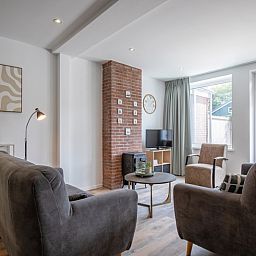 Lichte woonkamer van Vakantiehuis Slufterhoek 104 in De Cocksdorp, Texel met moderne meubels en grote ramen.