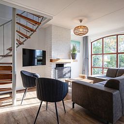 Gezellige woonkamer in Villapark Residentie Texel nr. 711, vakantiehuis in De Cocksdorp, Texel met moderne inrichting en grote ramen.