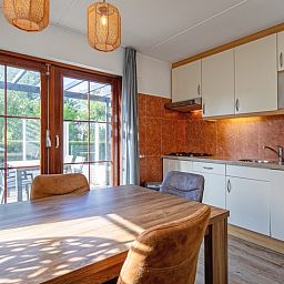 Gezellige keuken en eetruimte in Villapark Residentie Texel nr. 711, vakantiehuis in De Cocksdorp, Texel, met uitzicht op terras en tuin.