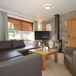 Gezellige woonkamer in Villa De Witte Hoek serre huisdiervrij, De Cocksdorp Texel, met comfortabele banken en een sfeervolle haard.