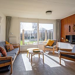 Lichte woonkamer van Vakantiehuis Slufteroord 292 in Bungalowpark Slufteroord, De Cocksdorp, Texel, met uitzicht op de tuin.