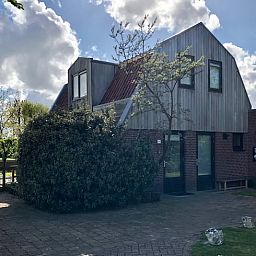Vakantiehuis in De Cocksdorp op Texel, Waddeneilanden, omgeven door groene natuur en een uitnodigend terras.