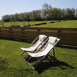 Relax in de ligstoelen van Vakantiehuis in De Cocksdorp, Texel, met uitzicht op groene velden en natuur op de Waddeneilanden.