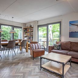Gezellige woonkamer in Vakantiehuis in De Cocksdorp, Texel met ruime zithoek en uitzicht op groene tuin, ideaal voor ontspanning op de Waddeneilanden.
