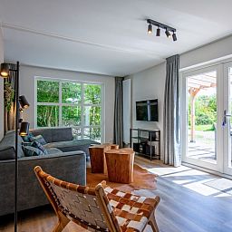 Bright living room of Holiday home D 690 in De Cocksdorp, Texel, with modern furnishings and views of the terrace and nature.