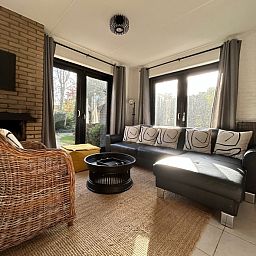 Gezellige woonkamer in Vakantiehuis C 059, De Cocksdorp, Texel met comfortabele zithoek en uitzicht op de tuin.