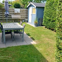 Gezellige tuin van Vakantiehuis B 223 in De Cocksdorp, Texel, met terras en groene omgeving voor een ontspannen verblijf op de Waddeneilanden.
