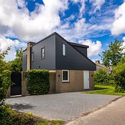 Vakantiehuis A 109 in De Cocksdorp, Texel, omgeven door groene natuur en blauwe lucht, ideaal voor een ontspannen verblijf op de Waddeneilanden.