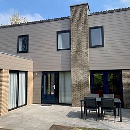 Vakantiehuis C 067 in De Cocksdorp, Texel, toont een modern terras met buitenmeubilair, ideaal voor ontspanning op de Waddeneilanden.