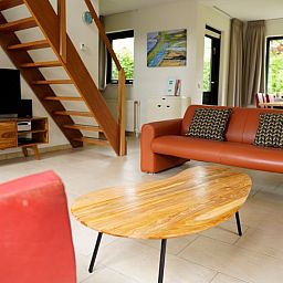 Gezellige woonkamer van Vakantiehuis C 067 in De Cocksdorp, Texel met comfortabele banken en een stijlvolle houten tafel.