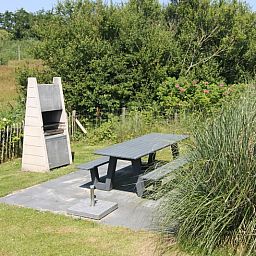 Geniet van de buitenruimte bij Vakantiehuis D 477 in De Cocksdorp, Texel met een gezellige barbecue en picknicktafel te midden van de natuur.