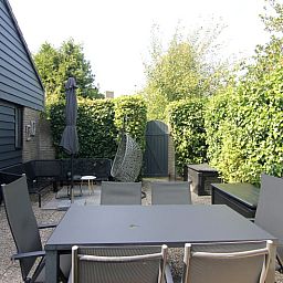 Geniet van de serene tuin van Vakantiehuis B 271 in De Cocksdorp, Texel, met comfortabel terras omgeven door groene natuur.