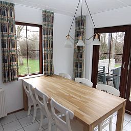 Cozy dining room in Holiday home D 745, De Cocksdorp, Texel overlooking green garden and spacious wooden table.