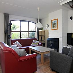 Gezellige woonkamer in Vakantiehuis D 531, De Cocksdorp, Texel. Comfortabele zitruimte met open haard en grote ramen met uitzicht op de natuur.