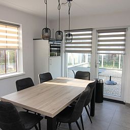 Moderne eetkamer in Vakantiehuis D 481, De Cocksdorp, Texel met ruime tafel en uitzicht op terras.