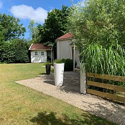 Vakantiehuis D 585 in De Cocksdorp, Texel, omgeven door groene natuur en een ruim terras, ideaal voor een ontspannen verblijf op de Waddeneilanden.
