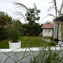 Ontspan in de tuin van Vakantiehuis D 585 in De Cocksdorp, Texel. Geniet van de groene omgeving en het rustige uitzicht op de Waddeneilanden.