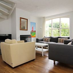 Gezellige woonkamer in Vakantiehuis D 622, De Cocksdorp, Texel. Comfortabele zithoek met uitzicht op de tuin, perfect voor ontspanning.