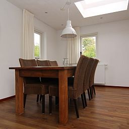 Eetkamer van Vakantiehuis D 622 in De Cocksdorp, Texel. Ruime binnenruimte met houten tafel, veel lichtinval en uitzicht op de natuur.