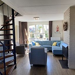 Gezellige woonkamer in Vakantiehuis E 417, De Cocksdorp, Texel met moderne inrichting en uitzicht op de groene omgeving.