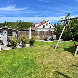 Geniet van de ruime tuin met schommel en terras bij Vakantiehuis D 728 in De Cocksdorp, Texel, ideaal voor ontspanning op de Waddeneilanden.