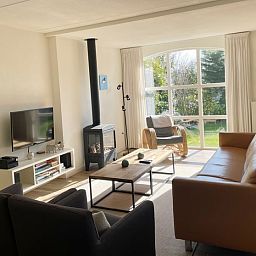 Gemuetliches Wohnzimmer im Ferienhaus D 748, De Cocksdorp, Texel mit moderner Einrichtung und grossen Fenstern fuer eine schoene Aussicht auf den Garten.