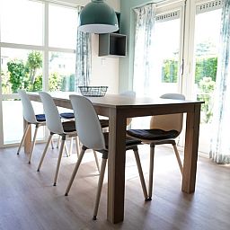Lichte eetkamer in Vakantiehuis D 770, De Cocksdorp, Texel. Geniet van het uitzicht op de tuin door de grote ramen van deze vakantiewoning.